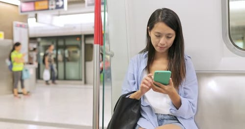Frau arbeitet am Handy im Bahnhof