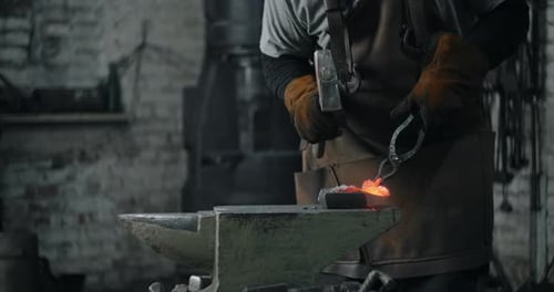Blacksmith Shaping Hot Metal on Anvil in Workshop