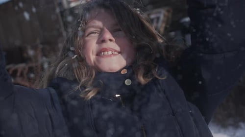 Kleines Mädchen genießt das Winterwetter und wirft in Slowmo Schnee in die Luft