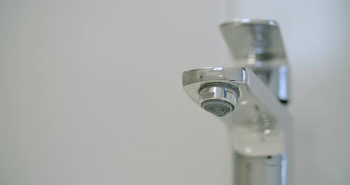Water Dripping From A Shiny Chrome Faucet