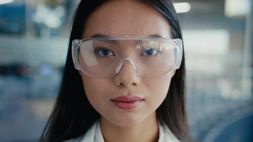Korean Female Scientist Wearing Protective Glasses And Lab Coat Indoors