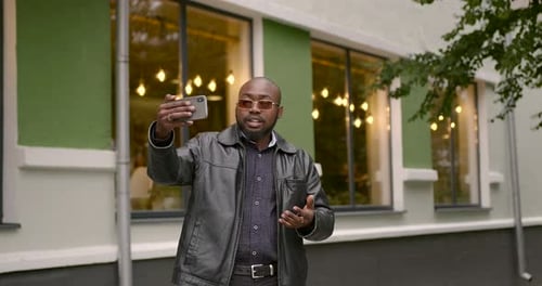Black Man Communicates Via Video Link Near a Cafe