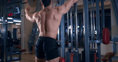 Bodybuilder Doing Exercise on the Simulator in the Gym