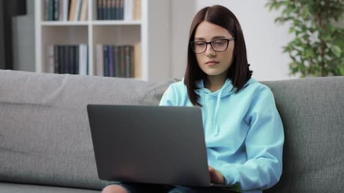 Young Woman Using Laptop on Couch at Home