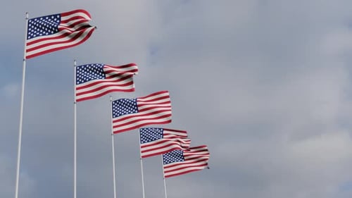 Waving American Flags on Poles Against a Cloudy Sky