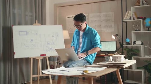 Asian Man Engineer Sitting On The Table And Using A Laptop To Work At The Office