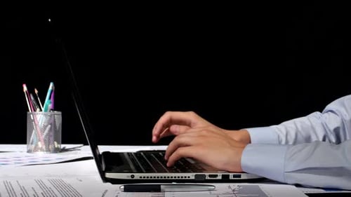 Hands typing on a laptop in an office