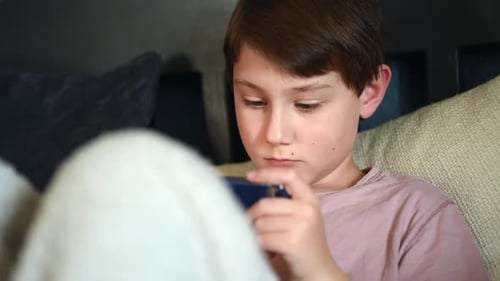 Boy Focuses on Mobile Device at Home