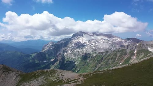 Aerial Shot of a Mountain Ridge Against Rocky Cliffs, Glacier and Snowy Peaks. Amazing Aerial View