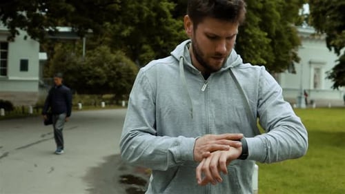 Man Checking Smart Watch in City Park