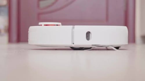 Robot Vacuum Cleaner Spinning on Wooden Floor