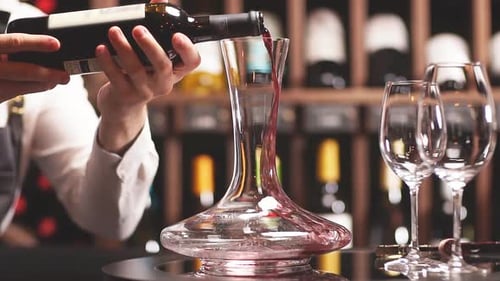 Sommelier qualifié versant le vin de la carafe dans un verre à vin
