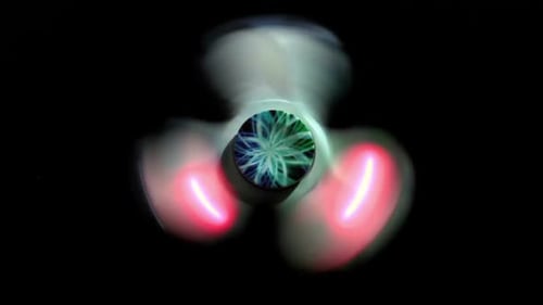 Illuminated Fidget Spinner Rotating Against Black Background
