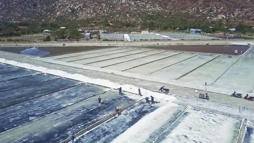 People Work on Marine Salt Fields By Rocky Hills