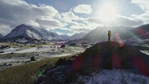 Silhouette of backpacker walking towards the edge of a rocky peak to contemplate the beautiful panor