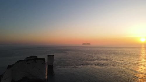 Colorful sky at sunset over sea and cruise ship in background, Old Harry Rocks cliff, England