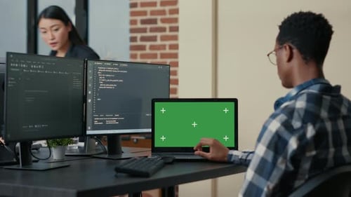 Designer de banco de dados escrevendo código usando laptop com tela verde Chroma Key Mockup sentado na mesa
