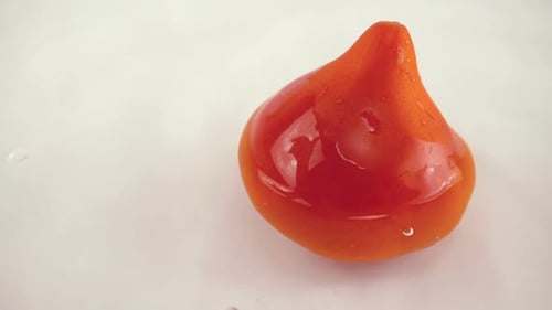 Rotierende reife Tomate in Wasser auf weißem Hintergrund. Zeitlupe.