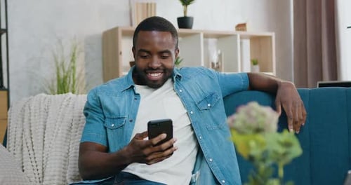 Smiling Man Using Mobile Phone on Blue Couch