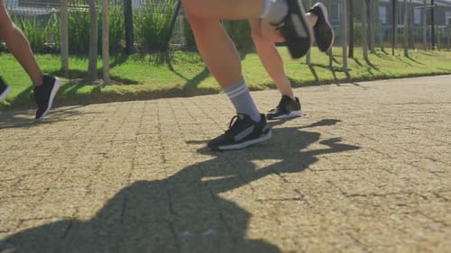 Group Legs Running on Paved Path in Daylight