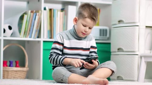 Child Uses Smartphone in Playroom