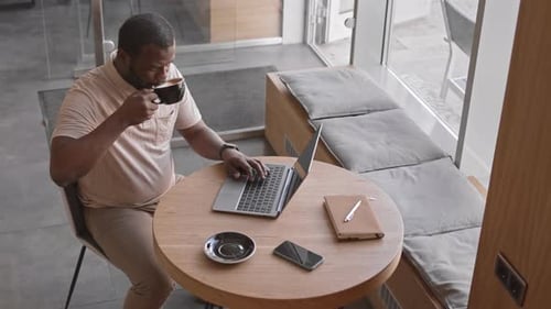 Black Man Working on Laptop in Cafe