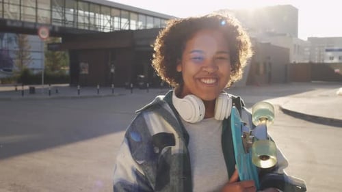 Smiling Young Adult Holding Skateboard Outside