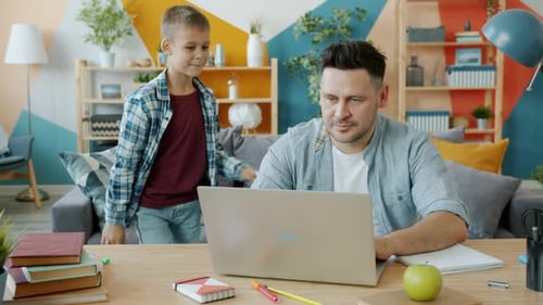 Adult and Child Looking at Laptop at Desk