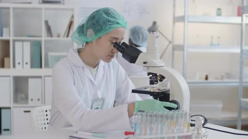 Smiling Scientist Works with Microscope in Laboratory