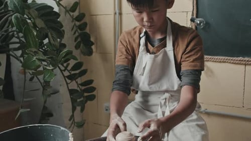Child Creates Pottery on a Wheel