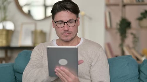 Man Using Tablet Device on Couch at Home