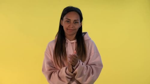 Woman Clapping Hands Against a Yellow Background