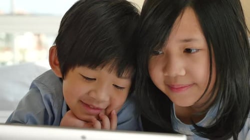 Cute Asian Children Lying In Bed And Using Laptop On White Bed