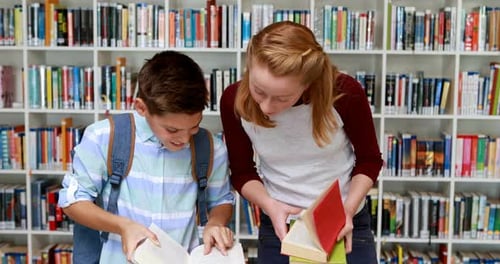 Smiling students reading book in library