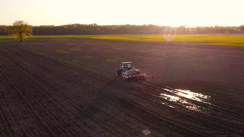 Tractor Working in Field at Sunset