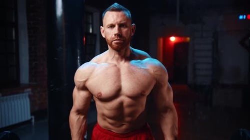 Tough Man Standing in the Gym and Lifts a Heavy Bar and Pumping His Hands Muscles