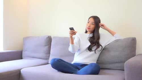 Woman Relaxing on Couch Using Remote
