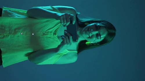 Smiling Woman Uses Mobile Phone with Colorful Lighting