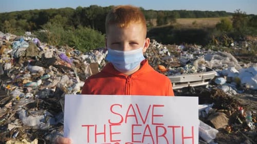Child Holding Save Earth Sign at Landfill