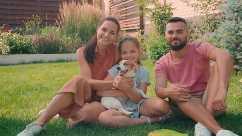 Happy Family with Dog Sitting on Lawn