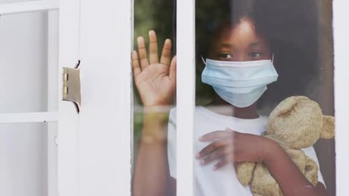Child with Mask Stands at Window Holding Bear