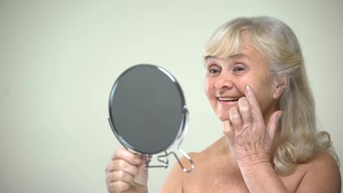 Senior Woman Applying Lotion to Her Face
