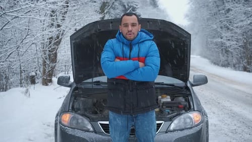 Man Standing By Car With Hood Open In Snow