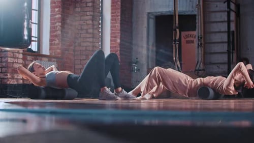 Two Skinny Women Training Together in the Gym Doing Exercises for Their Back
