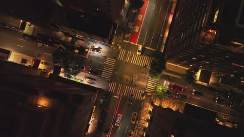Cars Driving on Street Between High Rise Buildings in Night City