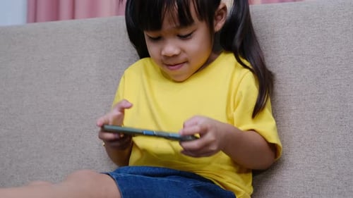 Little Girl Plays on Mobile Phone at Home