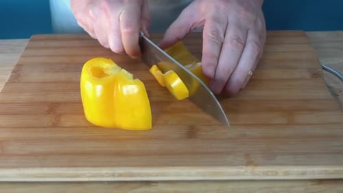 Person Slicing Yellow Pepper on Cutting Board