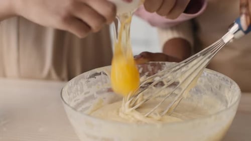 Child Cracks Egg into Bowl While Baking