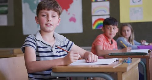 Boy smiling while sitting on his desk at school