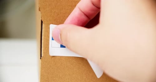 Hand Applies Made in Finland Label to Box